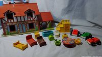 Fisher Price Play Family House with 15 colorful accessories including beds, stove, bathtub, dining table, sink, watering cans, and toy cars.
