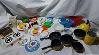 Wide view of a large assortment of vintage toy kitchen items on white background.