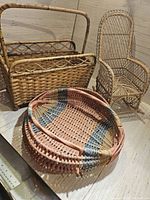 Full view of three wicker pieces: magazine rack, rocking chair, and tray basket displaying weave details and shape.