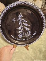 Vintage Blue Mountain Pottery Christmas plate from 1976 with textured Christmas tree design and decorative border.