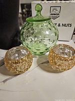 Photo showing the large green bubble glass jar with lid and two small amber bubble glass bowls together on a countertop.