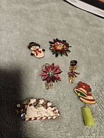 Lot of 5 brooches and 1 Christmas pin on neutral background showing all items