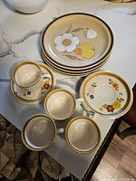Photo showing 4 cups and saucers with floral designs and 4 larger floral plates stacked showing both styles.