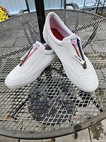 Side view of white Nautica runners showing zip-up front closure and logo tag on tongue.