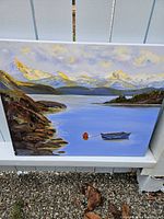 Photo of original oil painting of Vancouver Island bay scene with boat and mountains, showing canvas and frame edges