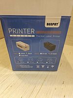Blue retail box of BEEPRT thermal label printer showing model BY-480/BY-480BT, features and compatible label colors.