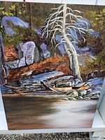 Front view of an original painting depicting a kayak and natural rocky riverbank with a distinctive light tree in a Vancouver Island setting.