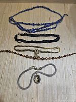 Photo of 4 vintage necklaces on a wooden surface showing colors and pendant details.