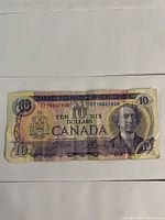 Front view of the 1971 Canadian ten dollar bill showing the portrait of Sir John A. Macdonald and serial number ETY4867928. Bill is worn with multiple creases.