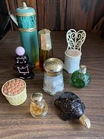 Photo showing nine vintage Avon collectible bottles and containers in various styles and materials.