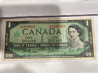 Front of 1957 Canadian Centennial One Dollar bill showing serial number, denomination and portrait of Queen Elizabeth II.