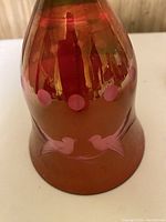 Close-up photo of cranberry glass bell base, showing etched design of two love birds and pink dots around the bell