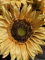 Close-up of a yellow faux sunflower showing detailed petals and realistic center with green and brown tones.