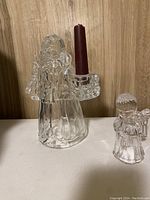 Glass Santa figure holding red candle on wooden floor