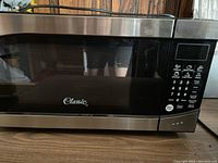 Front view of Classic microwave oven showing stainless steel finish and black control panel with numeric keypad and function buttons