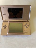 Gold Nintendo DS Lite handheld gaming console open, showing two screens and controls.