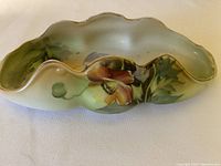 Side angle view showing hand painted floral design and scalloped edges with gold trim