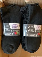Pack of 4 black ankle socks showing the front of the socks and label with brand and pack information.