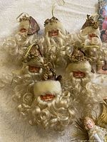 Photo of six small vintage gold angel head tree toppers with curly hair and decorative elements.