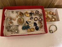 Photo of multiple pairs of vintage clip earrings in a box along with some brooches and costume jewellery pieces