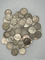 Overhead view of a scattered pile of US silver dimes showing obverse and reverse.