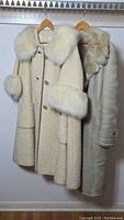 Overview of two coats: cream bouclé wool coat with fur trim and beige shearling coat