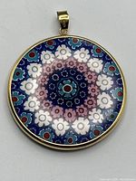Direct front view of circular millefiori glass pendant showing detailed floral pattern