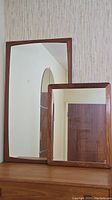 Overview showing both mirrors side by side on wood surface against wallpaper