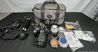 Overview of all lot contents including bag, camera, tripod, filters and accessories