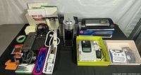 Overview photo of entire lot showing Nepresso coffee machine, laminating machine, power cords, label makers, stack of paper pads, adhesive notes, pens and power strips.