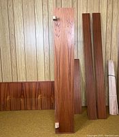 Multiple bed frame components leaning against wall, including headboard, footboard, side rails and slats