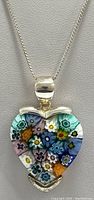 Close-up of front of heart-shaped pendant showing multicolored millefiori floral pattern
