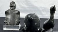 Overview of all three sculptures (figure on stand at left, seal center, loon right) on white background