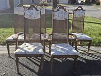 Front view of all five vintage dining chairs showing cane backs and floral cushions