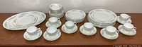 Full set of Wedgwood Westbury china laid out including plates, tea cups and saucers on wooden surface.