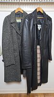 Two overcoats side by side: black leather Mario Zeli size 42 lined winter overcoat and herringbone tweed Aquascutum Ltd overcoat.