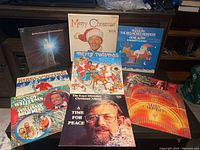 Wide view of 9 Christmas vinyl record album covers showing variety of artists and titles.