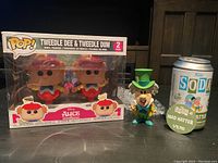 Photo of Tweedle Dee & Tweedle Dum 2-pack Funko Pop figures in packaging, alongside Mad Hatter Funko Soda figure and soda can.