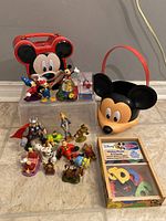Photo of the lot showing Mickey Mouse radio/case, bucket, various Disney character figurines, and boxed refrigerator magnets