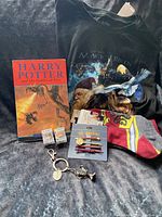 Photo showing Harry Potter and the Goblet of Fire book, black Harry Potter themed T-shirt, Gryffindor socks, two small hair clips, a keychain, and two mini Funko Pop figures.