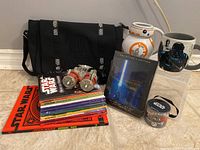 Photo showing Star Wars lot with 9 books, 2 mugs (BB-8, Darth Vader), sealed 3D Blu-ray collector's edition, toy bracelet set sealed, and Star Wars branded black shoulder bag