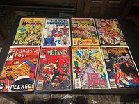 Eight Marvel comic books laid out flat on a surface, showing a variety of classic comic covers from the 1980s and 1990s.