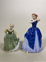 Front and angled view of two Royal Doulton porcelain figurines, Laura and Fair Maiden with clear detail on dresses and poses.