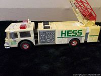 Side view of 1989 HESS Fire Truck showing white body, detailed decals, red wheels, and cab with HESS logo