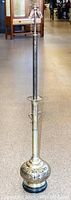 Full length image of tall brass floor lamp showing decorative base and overall condition.