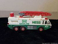 Front side view of 1996 Hess Emergency Ladder Truck toy showing white and green body with red ladder and wheels. Displays Hess and Gasoline branding with Amerada Petroleum references.