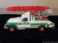 Side view of the 1994 HESS Rescue Ladder Truck showcasing the white and green livery with red ladder extended horizontally.