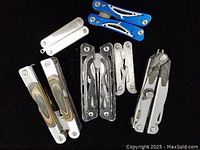 Top view of all 7 multi-tools arranged on dark surface showing variety of handles and types.