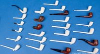 Full lot of 28 assorted wooden and white clay pipes laid out on blue background, showing variation in size, shape, color and condition.
