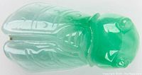 Top-down photo showing detailed carving on bug wings and head, translucent bright green jade color visible, polished surface.